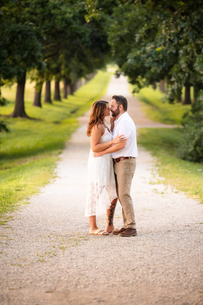 Engaged Couple Kissing with tree line in background