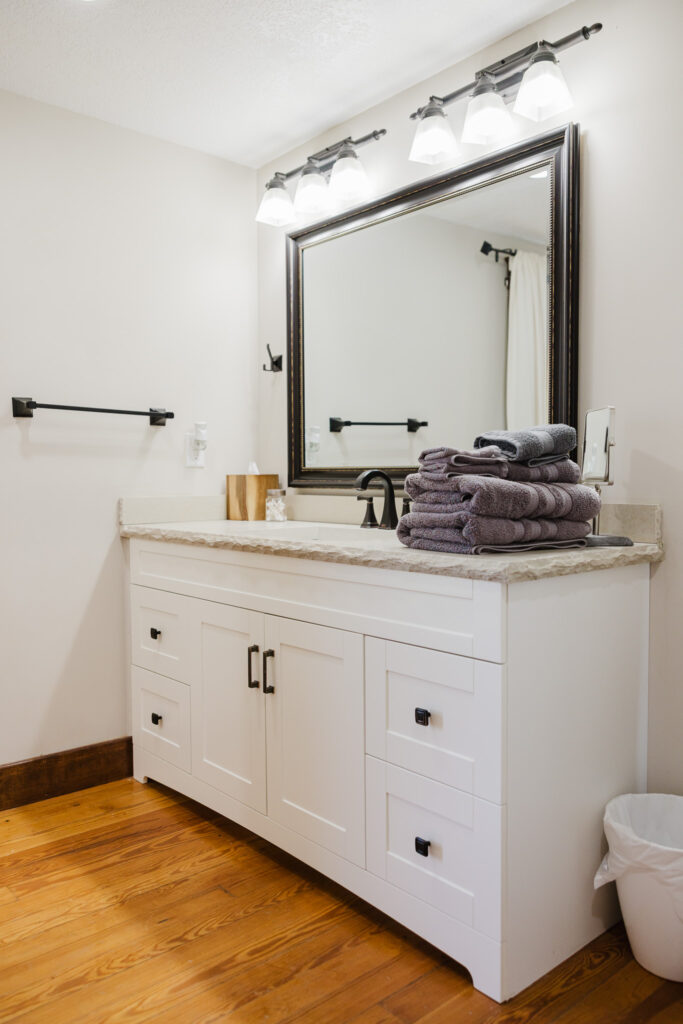 Refurbished white bathroom with black mirror an hollywood lighting.