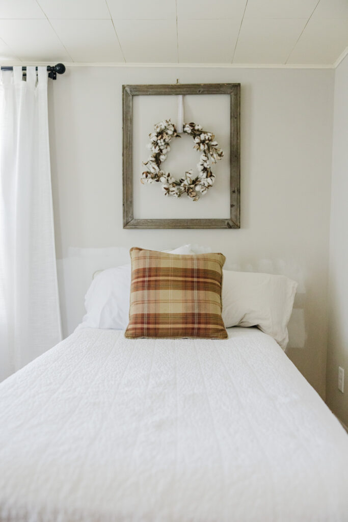 Bedroom with twin bed, small pillow and rustic decor.