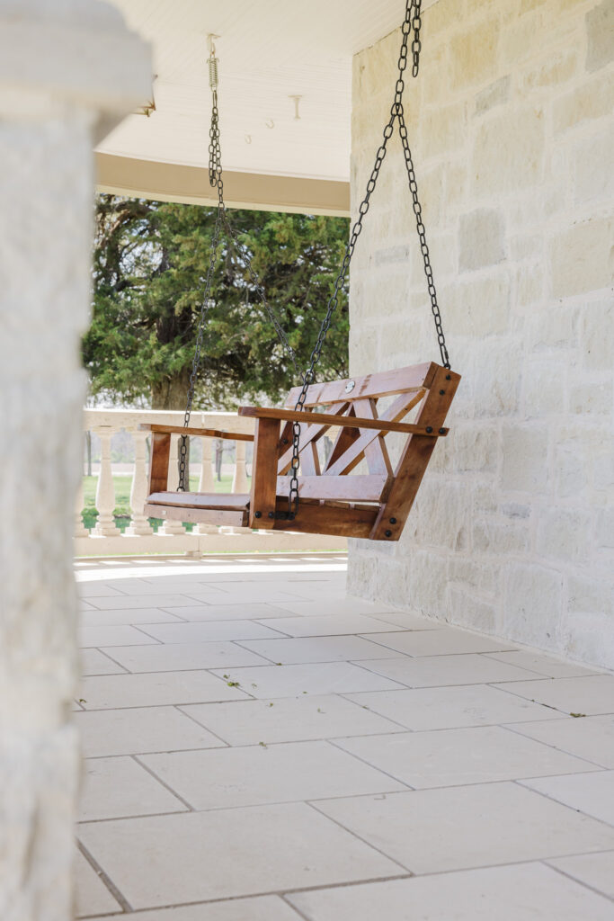 Porch swing with porch railing and tree in background
