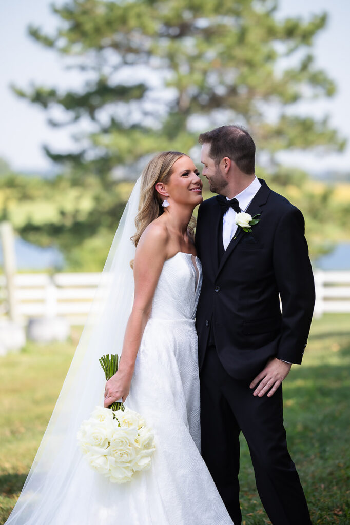 Bride and Groom looking at each other with lake in the background and wind in brides hair in overland Park