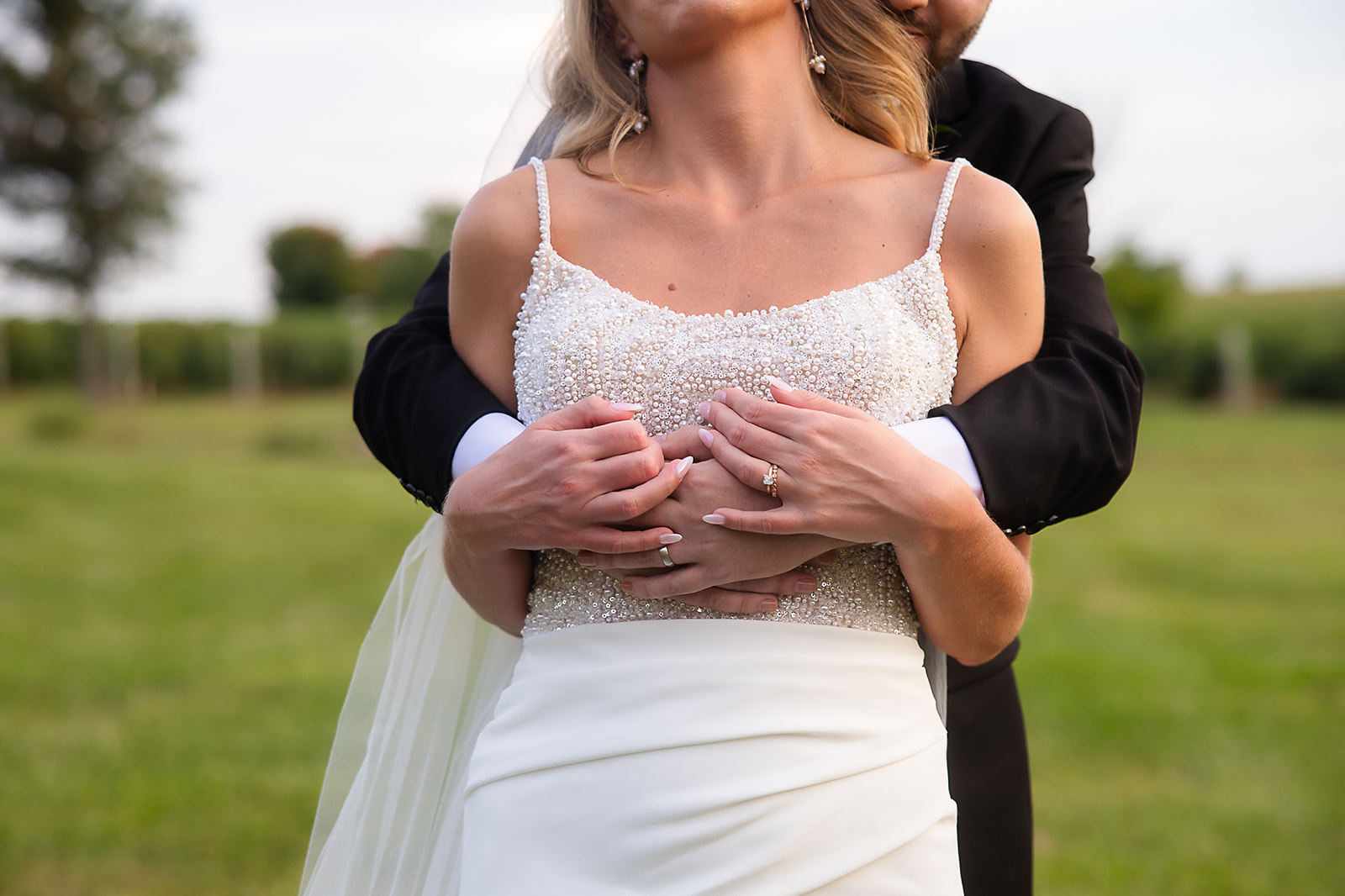 groom hugging bride from behind and bride leaning into groom