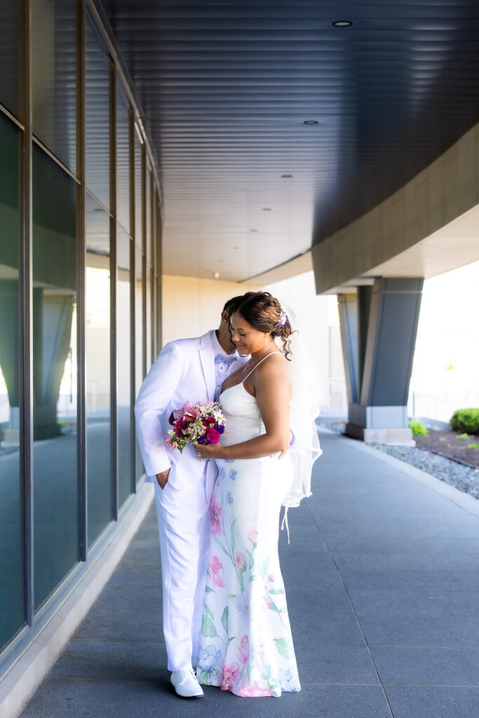 Bride and groom embracing outside modern building.