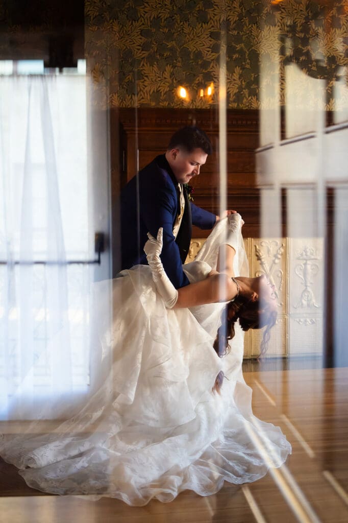 Bride and groom first dance with a long dip shot through a door at the Dillon House in Topeka, Kansas